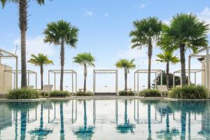 a swimming pool with palm trees in the background at Bona by Kozystay - Ciumbuleuit in Bandung