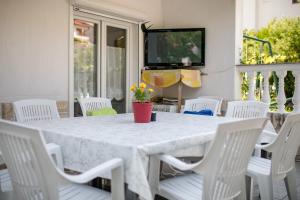 a white table with white chairs and a television on a patio at Apartment Daisy- excellent location close to Rab in Rab