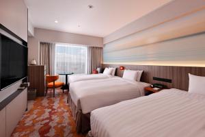 a hotel room with two beds and a flat screen tv at Miyako Hotel Yokkaichi in Yokkaichi