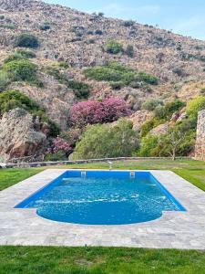 a blue swimming pool with a mountain in the background at Fintoz Butika in Karaburun