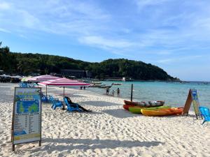 a beach with chairs and umbrellas and boats on it at Ohlala Guesthouse in Perhentian Islands +22 photos