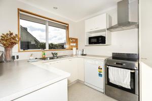 a kitchen with white appliances and a window at Convenient Westfield House 3bedroom 2bath in Christchurch