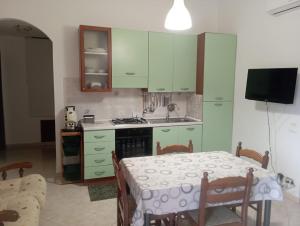 a kitchen with green cabinets and a table with a tablecloth at Casa vacanza Marta in Torrenova