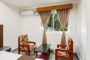 a bedroom with a bed and two chairs and a window at Nexstay Kassaba Inn in Kozhikode