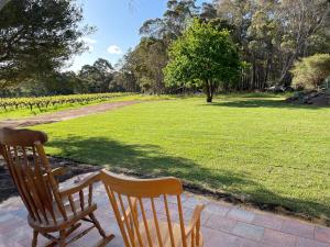 two wooden chairs sitting next to a field of grass at Patricias Garden Studio in Witchcliffe +23 photos