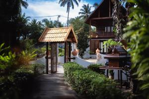 ein Haus mit einem Holzdach und einem Gehweg in der Unterkunft Leeloo Paradise in Khanom