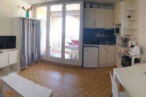 a kitchen with white cabinets and a large sliding glass door at Carnon-plages - Agréable Studio cabine in Mauguio