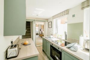 a kitchen with green cabinets and a counter top at Wigeon Cottage, Aldeburgh - Sleeps 4 - Adults only house in Aldeburgh