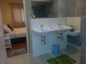 ein Badezimmer mit 2 Waschbecken und ein Schlafzimmer mit einem Bett in der Unterkunft Khanom Garden Suite in Khanom