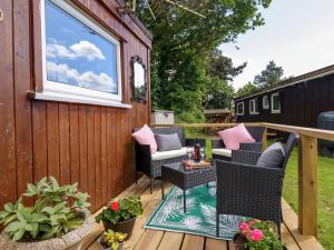 a deck with wicker chairs and a table at Chalet Forte in Aberdyfi