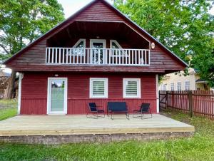 a red house with chairs on a deck at Tamme maja - Oak Tree House with big terrace and balcony in Tapa