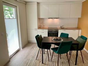 a kitchen with a table and green chairs in a room at Tamme maja - Oak Tree House with big terrace and balcony in Tapa