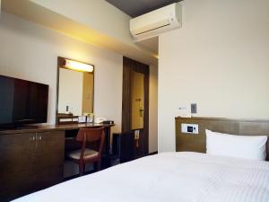 a hotel room with a bed and a desk and a television at Hotel Route-Inn Gifuhashima Ekimae in Hashima