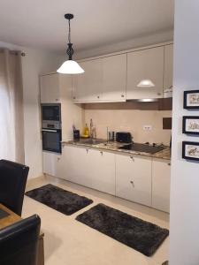 a kitchen with white cabinets and black appliances at Casa cu flori in Pantelimon