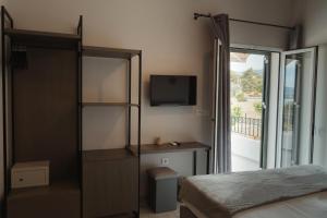 a bedroom with a bed and a tv and a balcony at Limanaki Hotel in Lassi