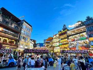 Une foule de gens marchant dans une rue avec des bâtiments dans l'établissement olivia Hotel, à Sa Pa