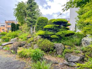 einen Garten mit Felsen, Sträuchern und Bäumen in der Unterkunft 自然豊かな古民家豪邸 最大12名まで可 大人数に最適可で アクセス良好な 菱閣 in Fujikawaguchiko