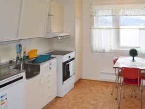 a kitchen with white appliances and a table with chairs at 6 person holiday home in Sandhornøy in Røssnes