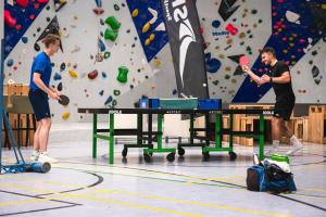two men playing ping pong in front of a climbing wall at Sport- & Seminarhotel Glockenspitze in Altenkirchen