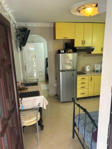 une cuisine avec des armoires jaunes, une table et un réfrigérateur dans l'établissement Apartman Pelcic,with WiFi and free parking, à Kostrena