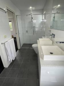 a white bathroom with two sinks and a toilet at Stunning Townhouse - 12 min CBD in Yarraville
