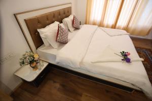 a bed with white sheets and pillows with flowers on it at Odbar Guest House Best Guest House at Leh Ladakh in Leh