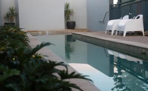 a group of white chairs sitting next to a swimming pool at Lennox Holiday Apartments in Lennox Head