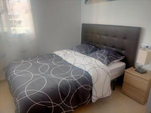 a bed with a black and white comforter and pillows at Apartamento a Torreblanca in Torreblanca