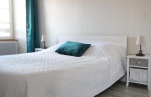 a white bed with a blue pillow on top of it at L'Escale - centre-ville et plage in Roscoff