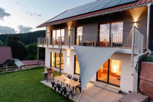 a house with a balcony with a table and chairs at Ferienwohnung Weitblick im Dahner Felsenland in Bruchweiler-Bärenbach