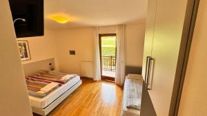 - une chambre avec un lit et une porte donnant sur un balcon dans l'établissement Residenza Arcobaleno, à Tenno