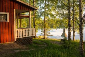 a red cabin with a view of a lake at Resort Naaranlahti in Punkaharju