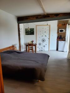 a bedroom with a bed and a table and a kitchen at Damvix Chambre d hôtes La Barbée in Damvix