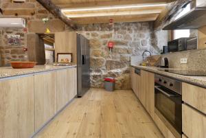 eine Küche mit Arbeitsflächen aus Holz und einer Steinmauer in der Unterkunft Casa da Marquinhas - Turismo Rural in Lama de Ouriço