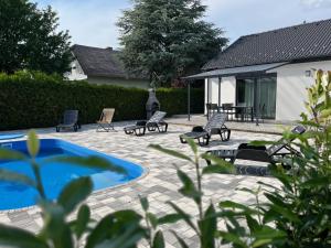 een patio met stoelen, een zwembad en een huis bij Dream Apartman Aliga II in Balatonvilágos