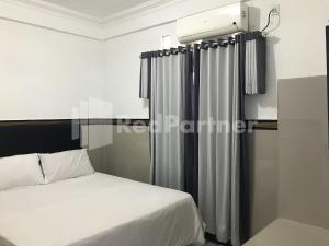 a bedroom with a bed and curtains in it at Hotel Gamary RedPartner Sidorejo in Pasuruan +14 photos