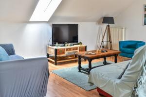 un salon avec une télévision et une table dans l'établissement Appartement spacieux et lumineux - Centre - Bord Loire - Climatisation - Wifi - Tout Confort, à Saumur