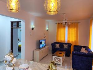 a living room with two blue chairs and a television at Spacious Two Bedroom Apartment In Mtwapa - Modern Amenities And Prime Location in Mombasa