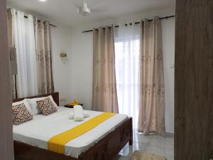 a bedroom with a bed and a window with curtains at Spacious Two Bedroom Apartment In Mtwapa - Modern Amenities And Prime Location in Mombasa