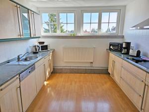 a kitchen with wooden floors and cabinets and windows at Ferienhaus Villa Maria - Ferienwohnung Chippendale in Kurort Gohrisch