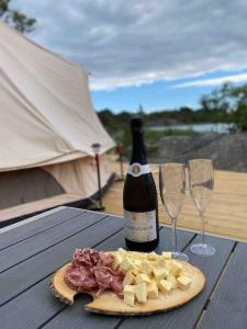 FöglöにあるHärligt privat Glamping med bastutältの木製テーブルにワイン1本とグラス2杯