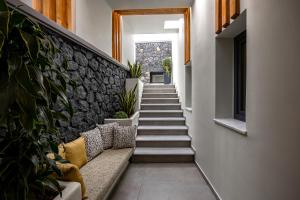 a stairway with a couch and a stone wall at Kudos Suites Firostefani in Fira