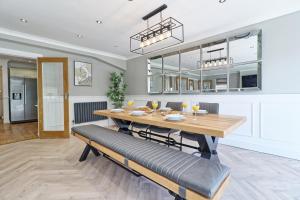 a dining room with a wooden table and benches at LMV Property - Modern Luxury Family Home in Theydon Bois With London Skyline Views in Theydon Bois