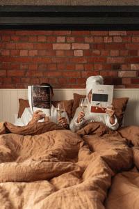 - deux personnes dormant dans un lit en lisant des livres et en buvant du vin dans l'établissement The Cobbler Hotel, à Wellington