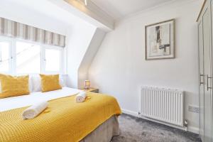 a bedroom with a bed with yellow sheets and a window at LMV Property - Modern Luxury Family Home in Theydon Bois With London Skyline Views in Theydon Bois