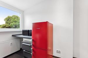 a red refrigerator in a kitchen with a window at Aarper Boutique Apartment I Messe, Airport, Netflix & Forest in Düsseldorf