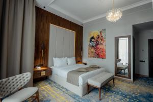 a bedroom with a large white bed and a chair at Qazaq Hotel Premium in Shymkent