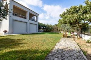 a house with a grass yard next to a building at "Kochili Villa" LUXURY VILLA in Áyios Andréas