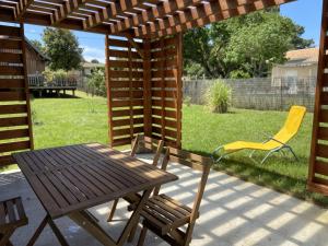 a patio with a table and chairs and a wooden pergola at Ma cabane Océan in Le Verdon-sur-Mer