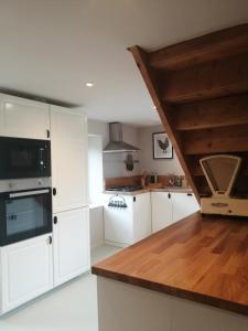 a kitchen with white cabinets and a wooden counter top at Moulin de Joumard, gîtes, chambres et table d'hôtes de charme , jacuzzi, sauna, piscine et bain nordique Etablissement 4 étoiles in Aubazat +45 photos